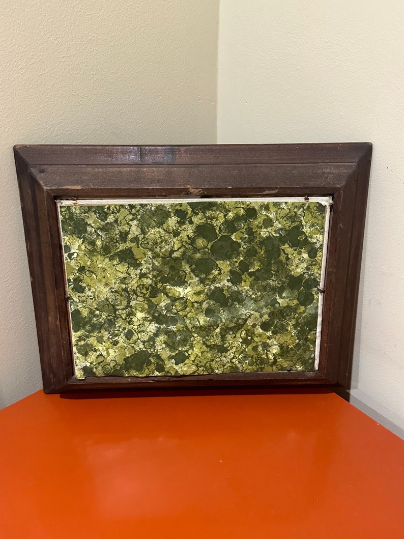 May include: A framed square picture with a green and yellow abstract design. The frame is dark brown wood.
