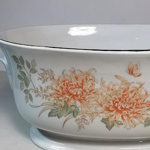 Puede incluir: Cuenco de cerámica blanco con un diseño floral con crisantemos naranjas y amarillos y una mariposa. El cuenco tiene un borde negro y una base, adecuado para servir platos.