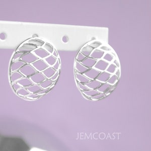 May include: A pair of silver earrings with a geometric, openwork design. The earrings are oval shaped and have a delicate, intricate pattern.
