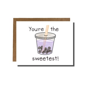 Pode incluir: Um cartão com uma ilustração em aquarela de um bubble tea. A bebida está em um copo transparente com um líquido roxo e pérolas de boba escuras. O texto no cartão diz "You're the sweetest!" O cartão tem uma borda marrom.