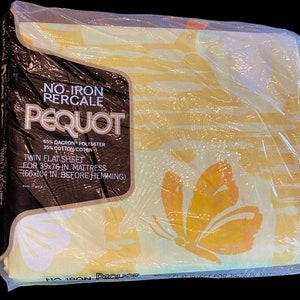 Op de afbeelding: Een geel en wit eenpersoonslaken met vlinderpatroon, verpakt in doorzichtig plastic. Het label vermeldt NO-IRON PERCALE PEQUOT, 65% DACRON POLYESTER, 35% KATOEN, LAKEN VOOR 99x193 CM MATRAS (168x264 CM VOOR HET ZOMEN).