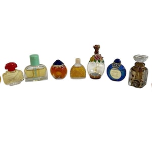 Pode incluir: Uma coleção de frascos de perfume em miniatura de várias formas e cores. Os frascos incluem vidro transparente, âmbar e azul, com tampas decorativas e detalhes florais. Alguns frascos têm rótulos.