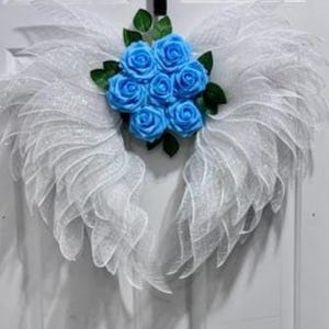 May include: White mesh angel wings with a cluster of light blue silk roses in the center.