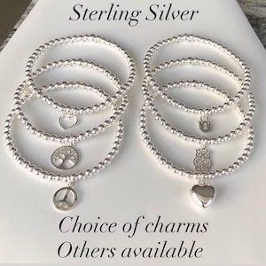 May include: Sterling silver bracelets with various charms, including a tree, heart, owl, and lock. The text "Choice of charms Others available" is below the bracelets.