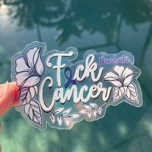 May include: A clear sticker with the words "F*ck Cancer" in white with a purple ribbon and the word "Pancreatic" in smaller white letters. The sticker is decorated with white flowers and leaves.