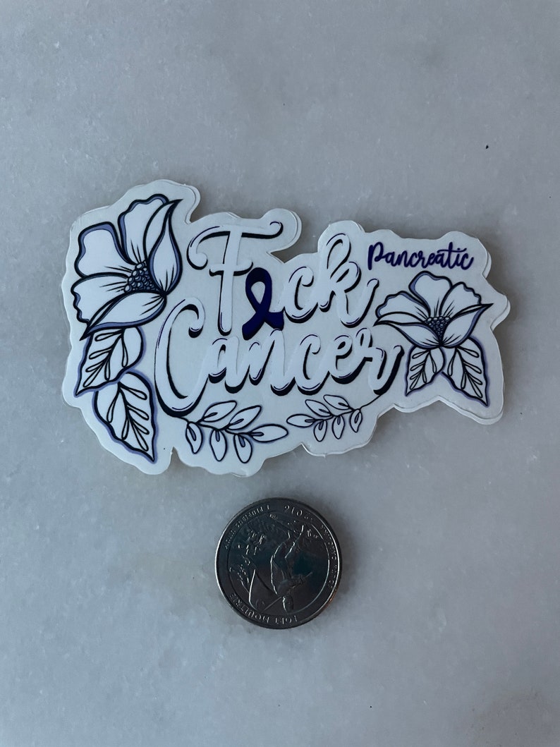 May include: A white sticker with black outline and purple ribbon. The sticker says "F*ck Cancer" with the word "Pancreatic" above the word "Cancer". The sticker is decorated with two black and white flowers.