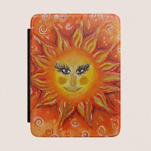 Puede incluir: Una funda rectangular para lector electrónico con una ilustración de un sol en tonos naranja y amarillo vibrantes. El sol tiene un rostro estilizado con pestañas oscuras largas, una sonrisa suave y puntas radiantes sobre un fondo de espirales blancas.