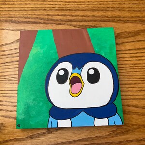 Puede incluir: Un lienzo pintado a mano con un pingüino de dibujos animados con plumas azules y blancas, un pico amarillo y una boca abierta de par en par. El pingüino está sobre un fondo verde y marrón.