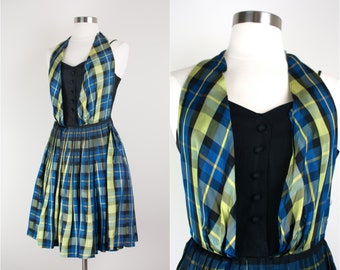 May include: A blue and yellow plaid dress with a black bodice and a halter top. The dress has a pleated skirt and a fitted bodice.