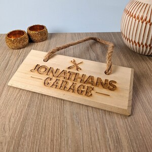 May include: Wooden sign with the text "Jonathan's Garage" and a wrench and screwdriver symbol. The sign has a rope for hanging.