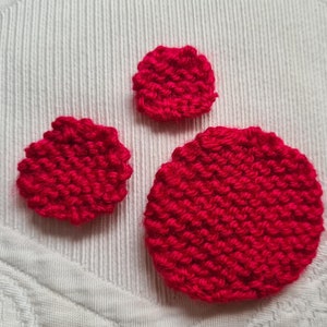May include: Three red knitted circles of varying sizes. The circles are made of a soft, textured yarn and are perfect for adding a touch of handmade charm to any project.