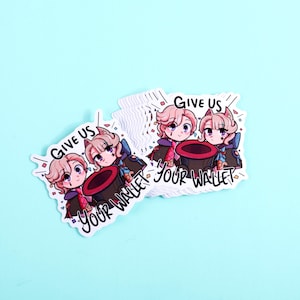 K&ouml;nnte beinhalten: Ein Stapel gestanzter Aufkleber mit zwei Anime-Figuren mit rosa Haaren und Katzenohren, die hinter einem gro&szlig;en Zylinder stehen. Der Text "GIVE US YOUR WALLET" ist in fetten schwarzen Buchstaben um die Figuren und den Hut gedruckt.