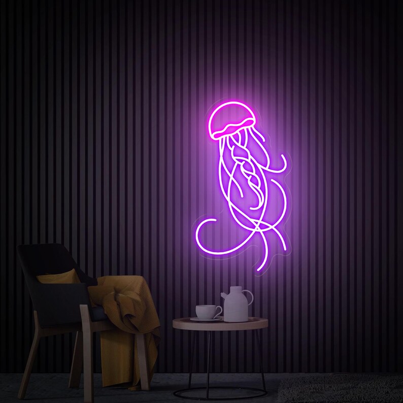 K&ouml;nnte beinhalten: Ein lilafarbenes Neon-Schild in Form einer Qualle mit flie&szlig;enden Tentakeln. Das Schild ist an einer dunklen Wand montiert, im Vordergrund befinden sich ein Stuhl und ein Tisch.