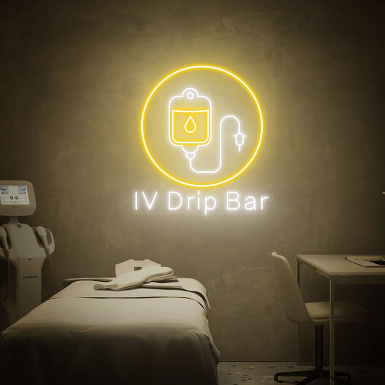 May include: A yellow neon sign with a white outline of an IV bag and a drip line. The sign reads "IV Drip Bar".