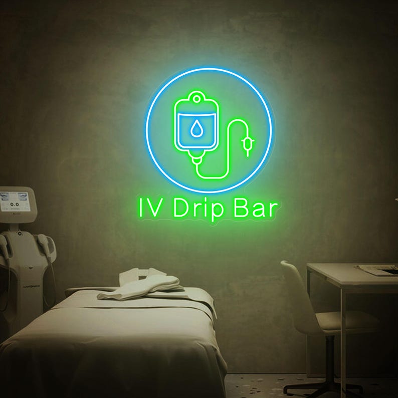 May include: A green neon sign with a blue circle around it. The sign depicts an IV bag with a drop of liquid and a tube. The text "IV Drip Bar" is below the sign.