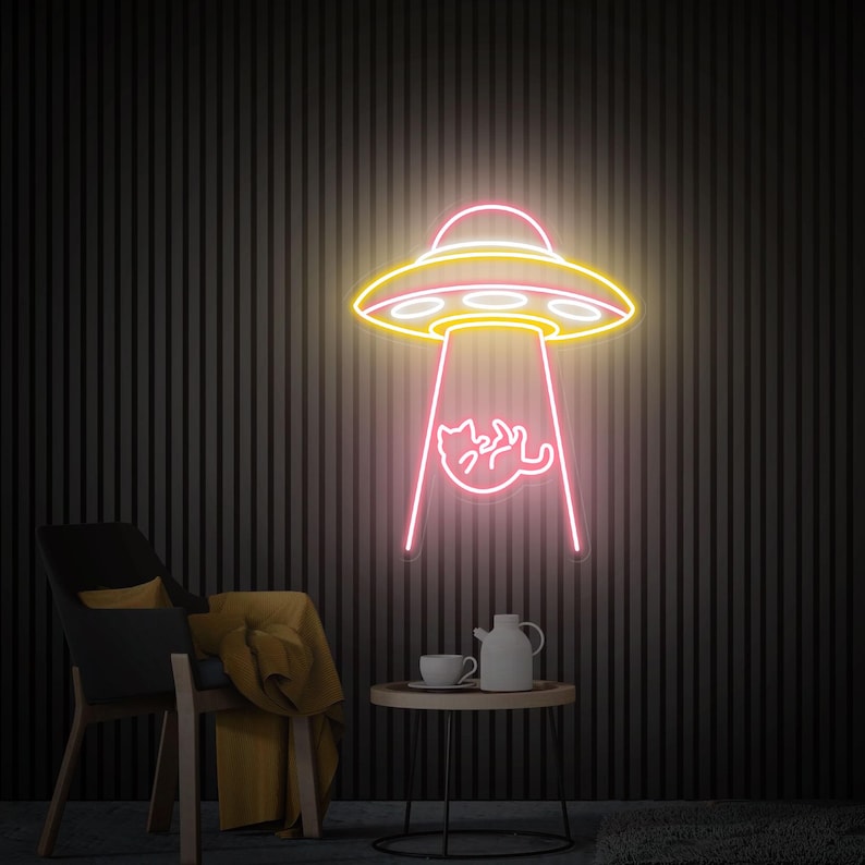 May include: A neon sign depicting a yellow and pink UFO with a pink beam of light, seemingly abducting a cat. The sign is mounted on a dark, vertically striped wall. A chair, table, and tea set are in the foreground.