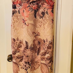 K&ouml;nnte beinhalten: Ein bodenlanges, &auml;rmelloses Kleid mit V-Ausschnitt. Das Kleid hat ein Blumenmuster in Rosa-, Burgunder- und Braunt&ouml;nen. Es hat ein eng anliegendes Oberteil und einen geraden Rock. Der Markenname "Adrianna Papell" ist sichtbar.
