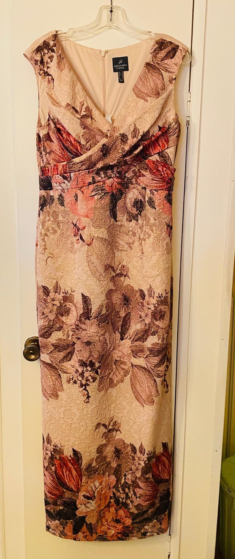 K&ouml;nnte beinhalten: Ein bodenlanges, &auml;rmelloses Kleid mit V-Ausschnitt. Das Kleid hat ein Blumenmuster in Rosa-, Burgunder- und Braunt&ouml;nen. Es hat ein eng anliegendes Oberteil und einen geraden Rock. Der Markenname "Adrianna Papell" ist sichtbar.
