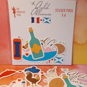 Puede incluir: Un paquete de pegatinas con varios diseños ilustrados, incluyendo una botella, un unicornio, un cruasán y un gallo. El paquete incluye el texto "STICKER PACK X 6" y "The Guild Alliance". Las pegatinas son coloridas y caprichosas.