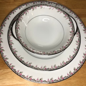 Könnte beinhalten: Eine weiße Porzellanschale mit floralem Muster und goldfarbenem Rand. Die Schale ist in einen größeren weißen Porzellanteller mit ähnlichem floralem Muster und goldfarbenem Rand eingebettet.