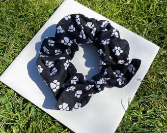 May include: Black and white scrunchie with a paw print pattern.