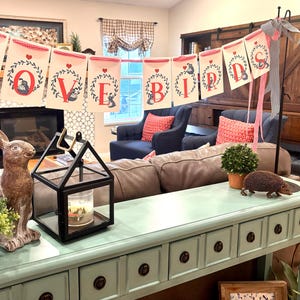 May include: A white ceramic mug with a black handle and the text "But First, Coffee" in a black, handwritten-style font. The mug is on a white surface.