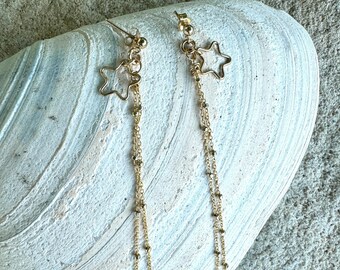 May include: Gold star dangle earrings with multiple chains. The chains are made of small gold beads.