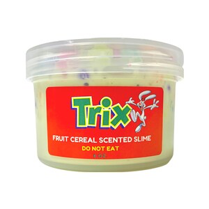 Op de afbeelding: Een doorzichtige plastic container met groene slijm met kleurrijke sprinkels. De container heeft een rood label met het Trix-ontbijtgranenlogo en de tekst "Fruit Cereal Scented Slime" en "Do Not Eat".