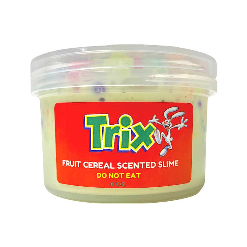 Op de afbeelding: Een doorzichtige plastic container met groene slijm met kleurrijke sprinkels. De container heeft een rood label met het Trix-ontbijtgranenlogo en de tekst "Fruit Cereal Scented Slime" en "Do Not Eat".