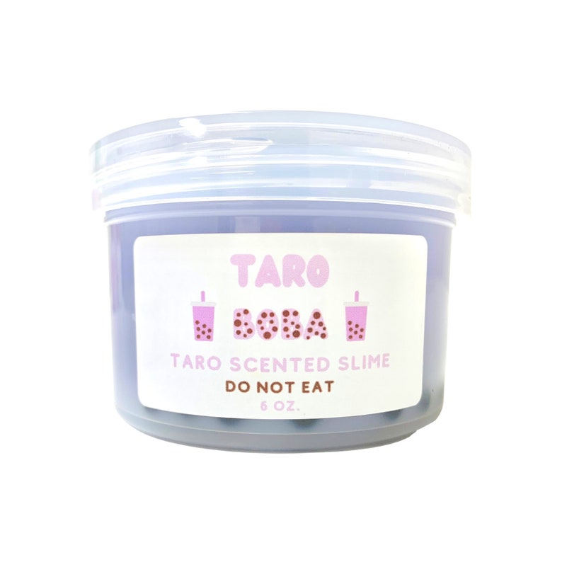 May include: A clear plastic container of purple taro scented slime with boba tea cups printed on the label. The label reads "Taro Boba" and "Taro Scented Slime". It also says "Do Not Eat" and "6 oz."