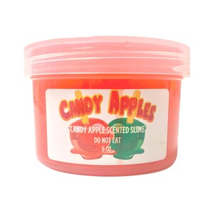 Könnte beinhalten: Ein roter Plastikbehälter mit Schleim, der nach Apfelbonbons riecht. Das Etikett lautet "Candy Apples" mit einem Bild von zwei Apfelbonbons. Das Etikett lautet auch "Candy Apple Scented Slime, Do Not Eat, 6 oz."
