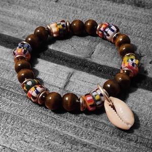 May include: A brown wooden beaded bracelet with colorful patterned beads and a white seashell charm.