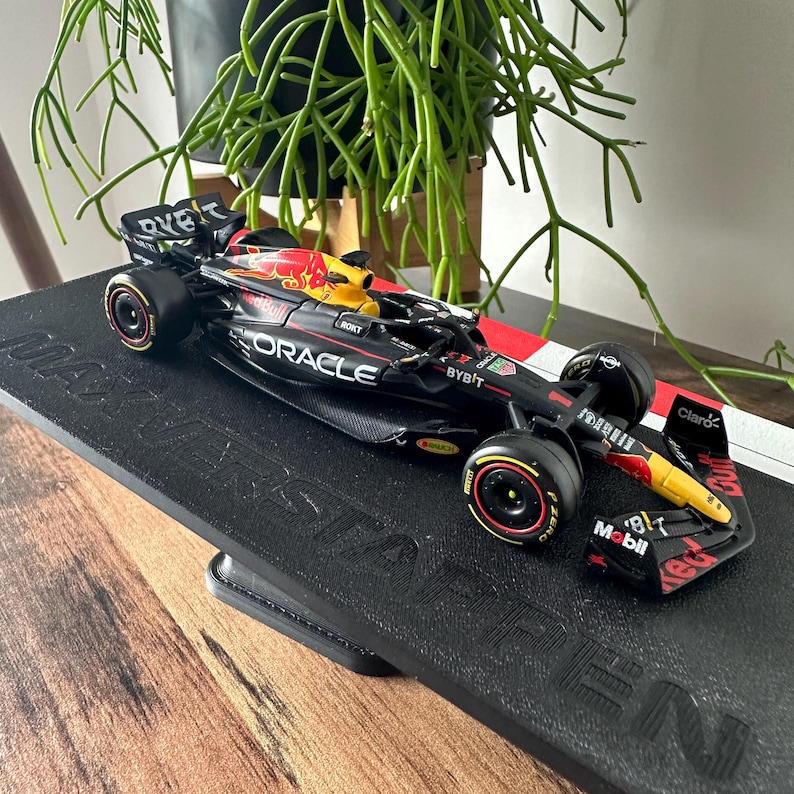 May include: A black and yellow Formula 1 race car model with the Oracle and Bybit logos. The car is on a black display stand with the word "Masterpiece" printed on it.