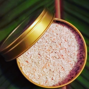 May include: A gold metal container with a lid, filled with small, white and pink, crushed seashells.