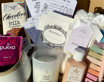 May include: A gift box containing a Chocolove milk chocolate bar, Pukka elderberry and echinacea tea, a ceramic mug, a Black Cedar soy candle, a reading log, book tracker cards, white chenille crew socks, and a set of colorful adhesive page markers.