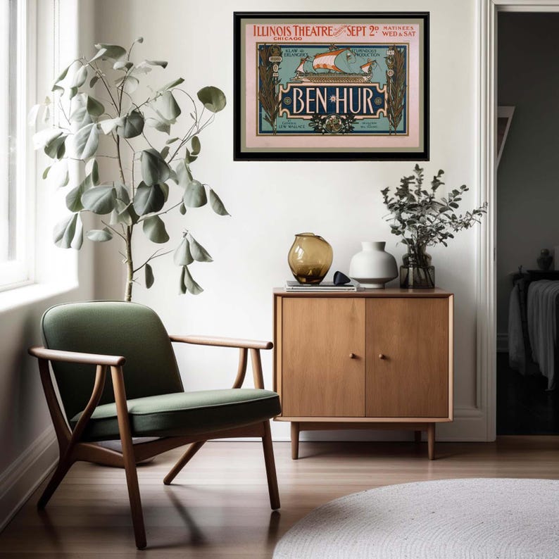 K&ouml;nnte beinhalten: Innenaufnahme mit einem gerahmten Vintage-Poster f&uuml;r das Theaterst&uuml;ck "Ben-Hur" in einem schwarzen Rahmen. Das Poster h&auml;ngt an einer wei&szlig;en Wand &uuml;ber einem Holzschrank. Ein gr&uuml;ner Stuhl und eine Topfpflanze befinden sich im Vordergrund.