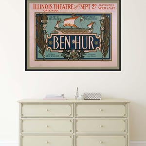 K&ouml;nnte beinhalten: Gerahmtes Vintage-Poster f&uuml;r das Theaterst&uuml;ck "Ben Hur" im Illinois Theatre in Chicago. Das Poster zeigt ein Schiff mit orangefarbenen Segeln und den Text "Ben Hur" in dekorativer Schrift. Das Poster h&auml;ngt &uuml;ber einer cremefarbenen Kommode mit sechs Schubladen.