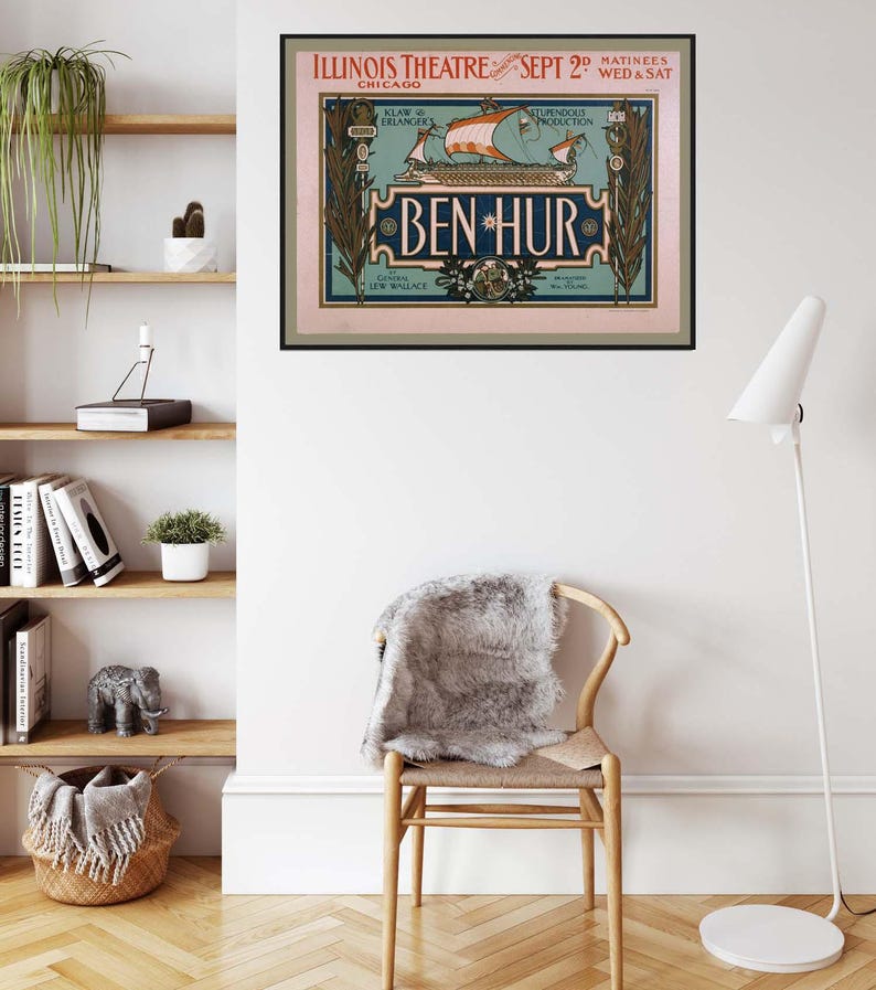 K&ouml;nnte beinhalten: Ein gerahmtes Vintage-Poster f&uuml;r das Theaterst&uuml;ck "Ben Hur" h&auml;ngt an einer wei&szlig;en Wand. Das Poster zeigt eine Schiffsillustration mit dem Text "Illinois Theatre Chicago" und "Sept 2". Unter dem Poster steht ein Holzstuhl mit einem grauen Fell.