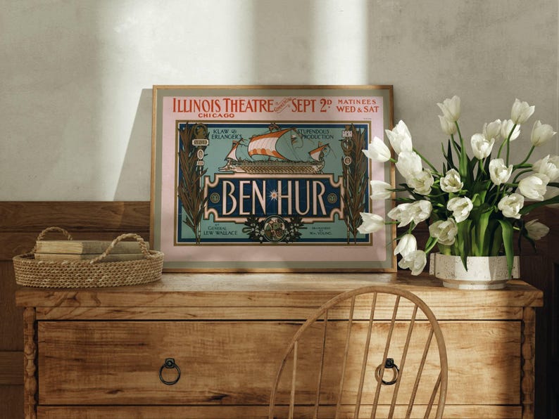 K&ouml;nnte beinhalten: Gerahmtes Vintage-Poster f&uuml;r die Produktion von "Ben-Hur" im Illinois Theatre, Chicago, vom 2. September. Das Poster, in einem goldenen Rahmen, zeigt eine Schiffsillustration. Es steht auf einer Holzkommode mit Korb und Blumen.