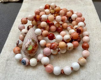 May include: A long necklace made of pink, white, and brown beads with a teardrop-shaped opal pendant.