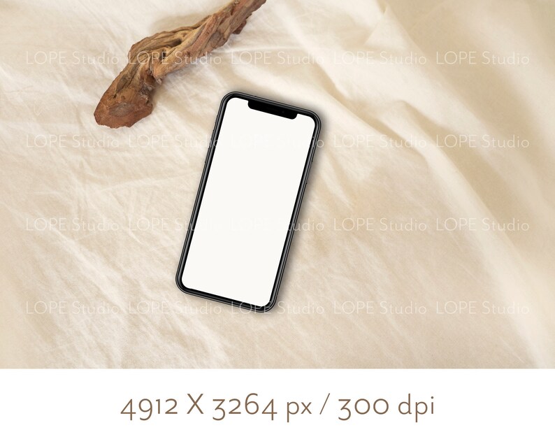 Pu&ograve; includere: Uno smartphone nero con uno schermo bianco &egrave; sdraiato su una superficie di tessuto beige. Un pezzo di legno alla deriva si trova nell'angolo in alto a sinistra dell'immagine.