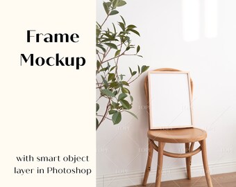 May include: A white frame mockup on a wooden chair with a green plant in the background. The frame is on a white wall and the chair is on a wooden floor.