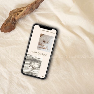 Pu&ograve; includere: Uno smartphone che mostra un sito web con il testo "minimal & slow lifestyle" e immagini di un letto bianco con un libro e un paio di occhiali su una superficie bianca.