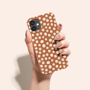 Puede incluir: Una funda de teléfono marrón con un patrón de lunares blancos.