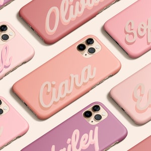 May include: A collection of pink and peach iPhone cases with names printed in a white, stylized font. The names include Olivia, Sophia, Rachel, Ciara, Emma, Elise, Bailey, and Mia.