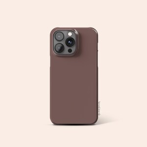 Puede incluir: Funda de teléfono marrón con módulo de cámara. La funda tiene un color liso y uniforme y un acabado brillante. El módulo de la cámara es de color marrón oscuro. La funda está diseñada para proteger el teléfono.