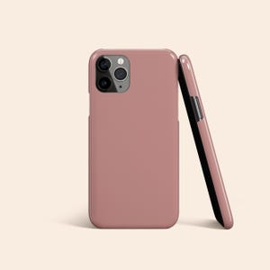 Può includere: Due custodie per telefono rosa antico. Una custodia è in posizione verticale, mostrando le lenti della fotocamera. La seconda custodia è appoggiata alla prima, rivelando un interno nero. Le custodie hanno una finitura liscia e opaca.