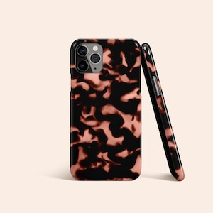 May include: A black and pink tortoiseshell phone case with a camera cutout.