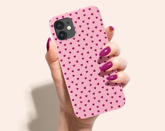 May include: A pink phone case with a pattern of small pink hearts. The case is being held in a hand with pink nail polish.
