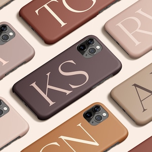 Puede incluir: Una colección de fundas para teléfono de diferentes colores e iniciales. Las fundas están hechas de un material suave y texturizado y tienen un diseño moderno y minimalista.